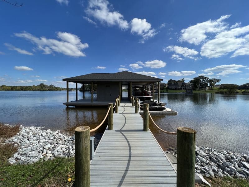 Gray composite walkway with rope railings leading out to the covered boat dock