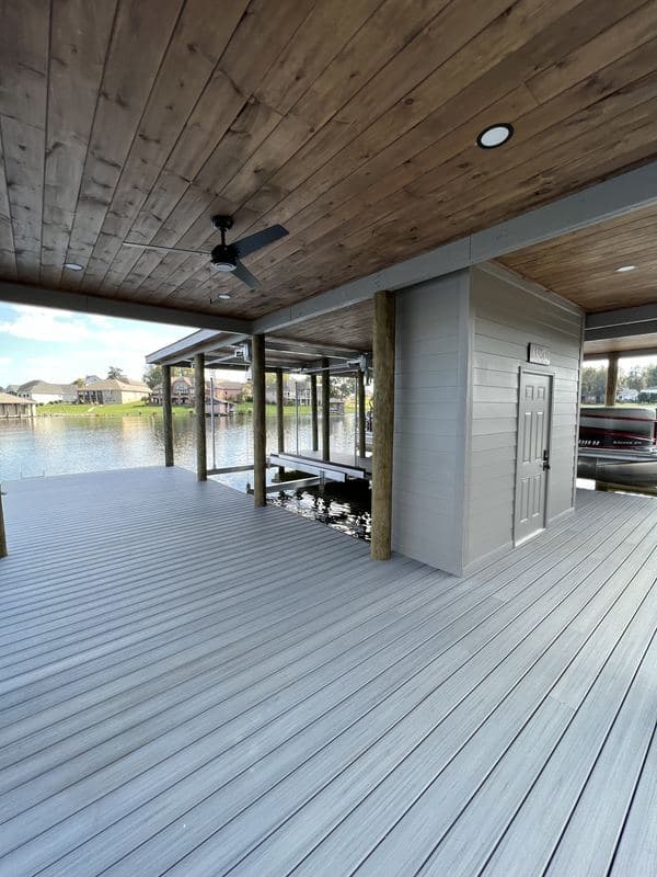 Covered dock lounge with a wood plank ceiling, ceiling fan, and enclosed storage room