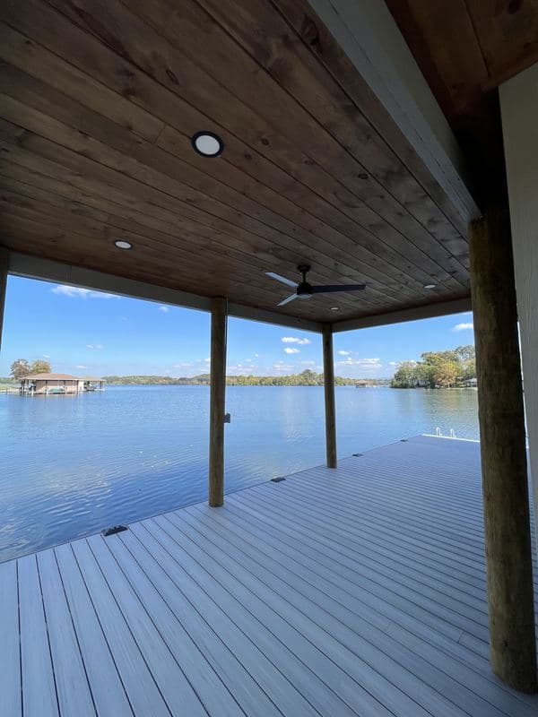 Open covered deck with ceiling fan and timber posts framing the lake view