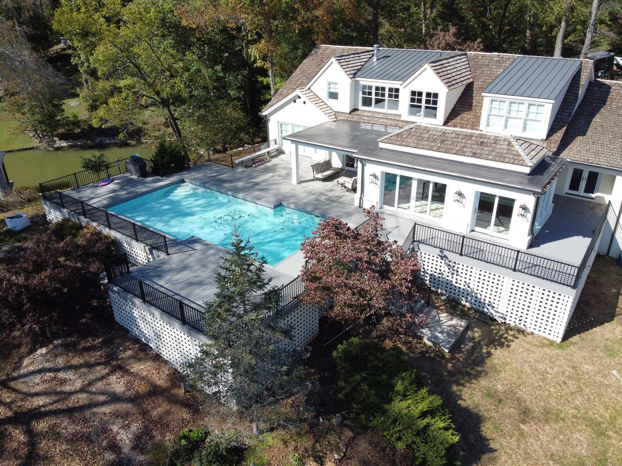 Aerial view of a gray composite wraparound deck with black metal railings around a pool and white home in Knoxville, TN