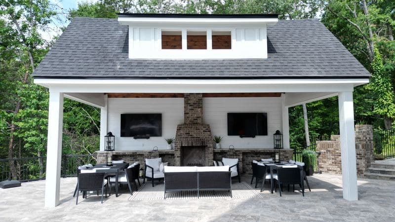 Front view of the pavilion with stone fireplace, TVs, and dining and lounge areas