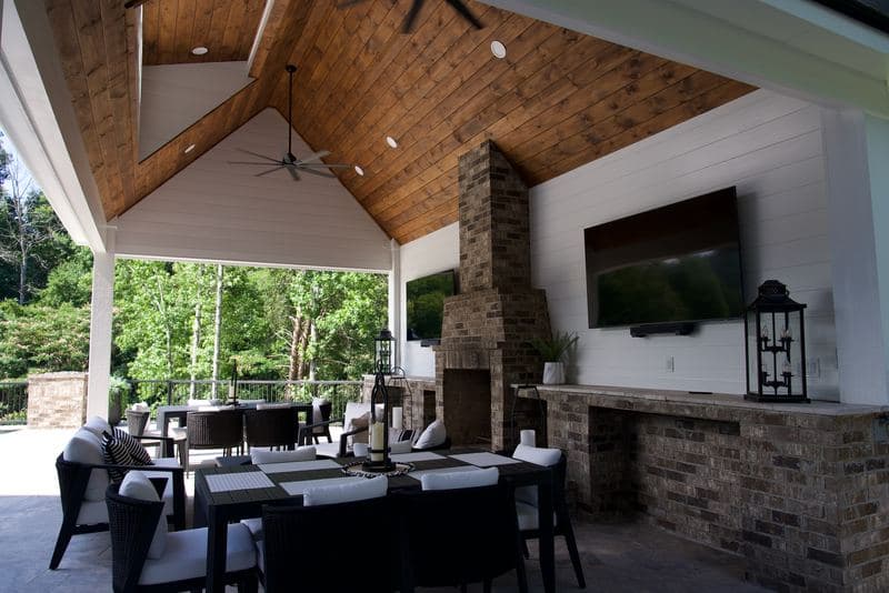 Covered outdoor dining under the pavilion beside the stone fireplace