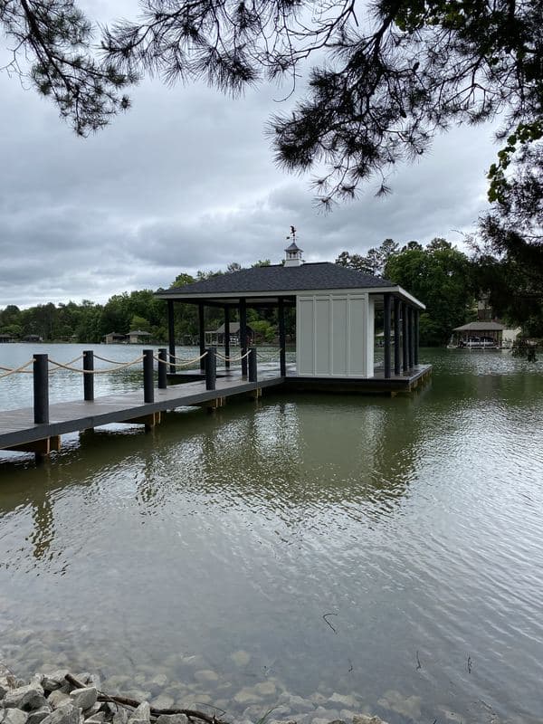 Covered boat dock with a cupola roof and enclosed storage room on a wooded lake
