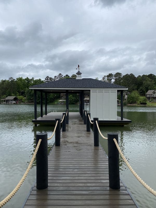 Dark-stained walkway with rope railings leading to the covered dock