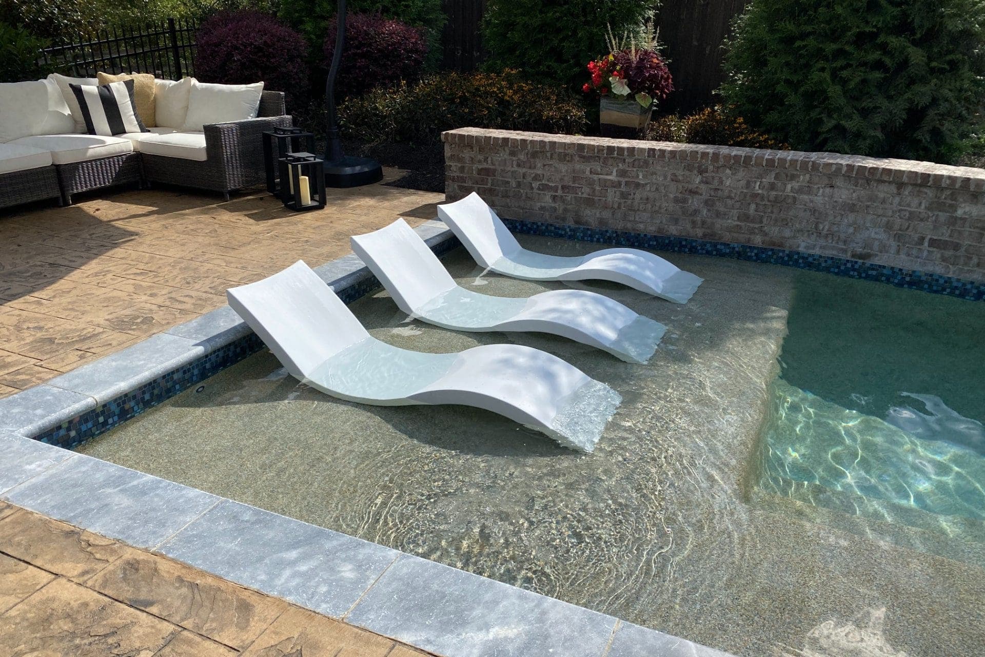 In-pool lounge chairs on a sun shelf beside a stone seat wall in Knoxville, TN