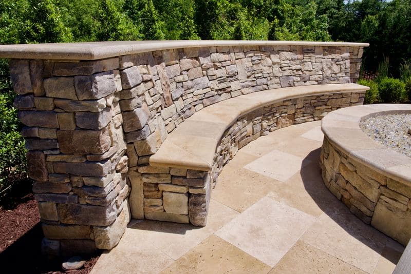 Curved stacked-stone seat wall with cap stones wrapping the fire-pit terrace