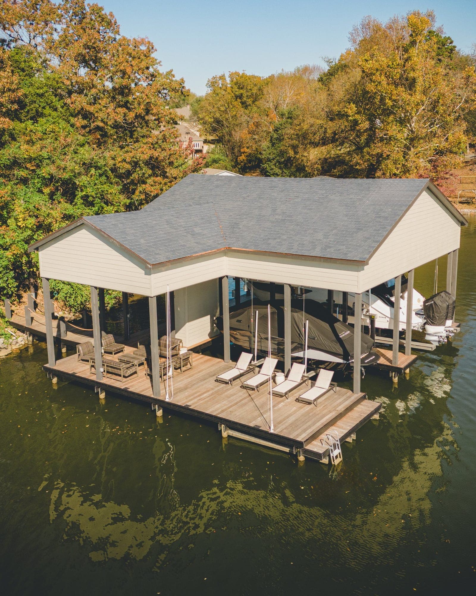 Covered boat dock with a shingle roof and lounge chairs on the deck, on Fort Loudoun Lake in Knoxville, TN