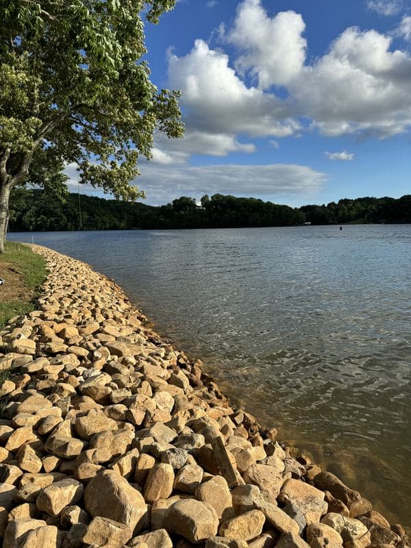 Low-angle view of a river rock shoreline stretching along the lake edge on a sunny day