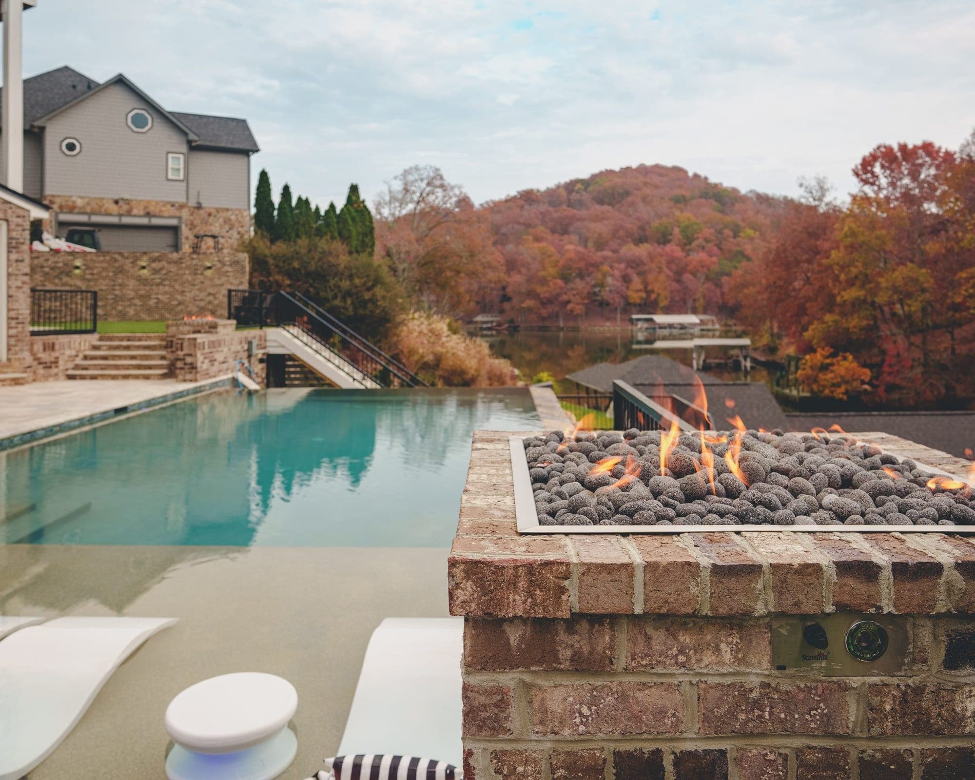 Infinity-edge pool with a stone fire pit overlooking a wooded valley in Knoxville, TN