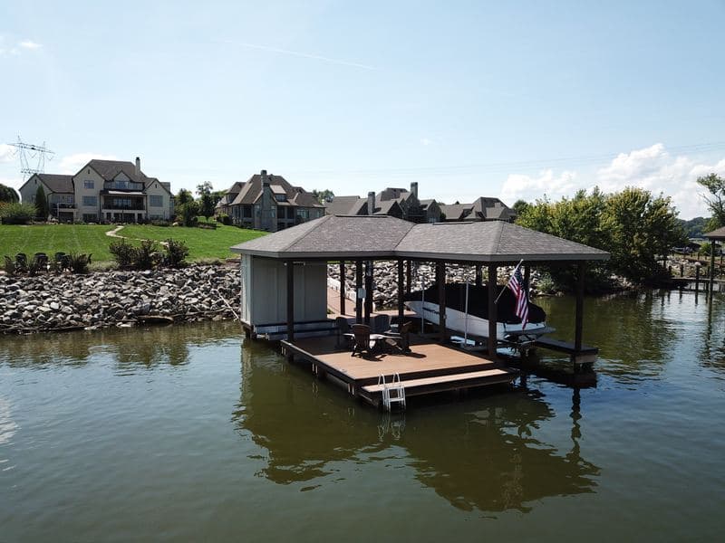 Covered dock with seating area in front of lakefront homes